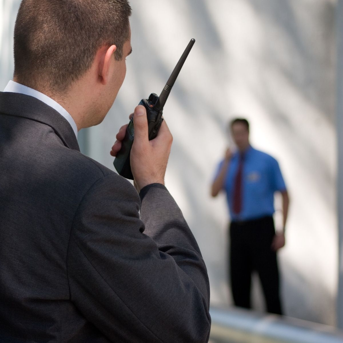 Agent de sécurité privé en uniforme ajustant son équipement lors d’une intervention en milieu urbain.